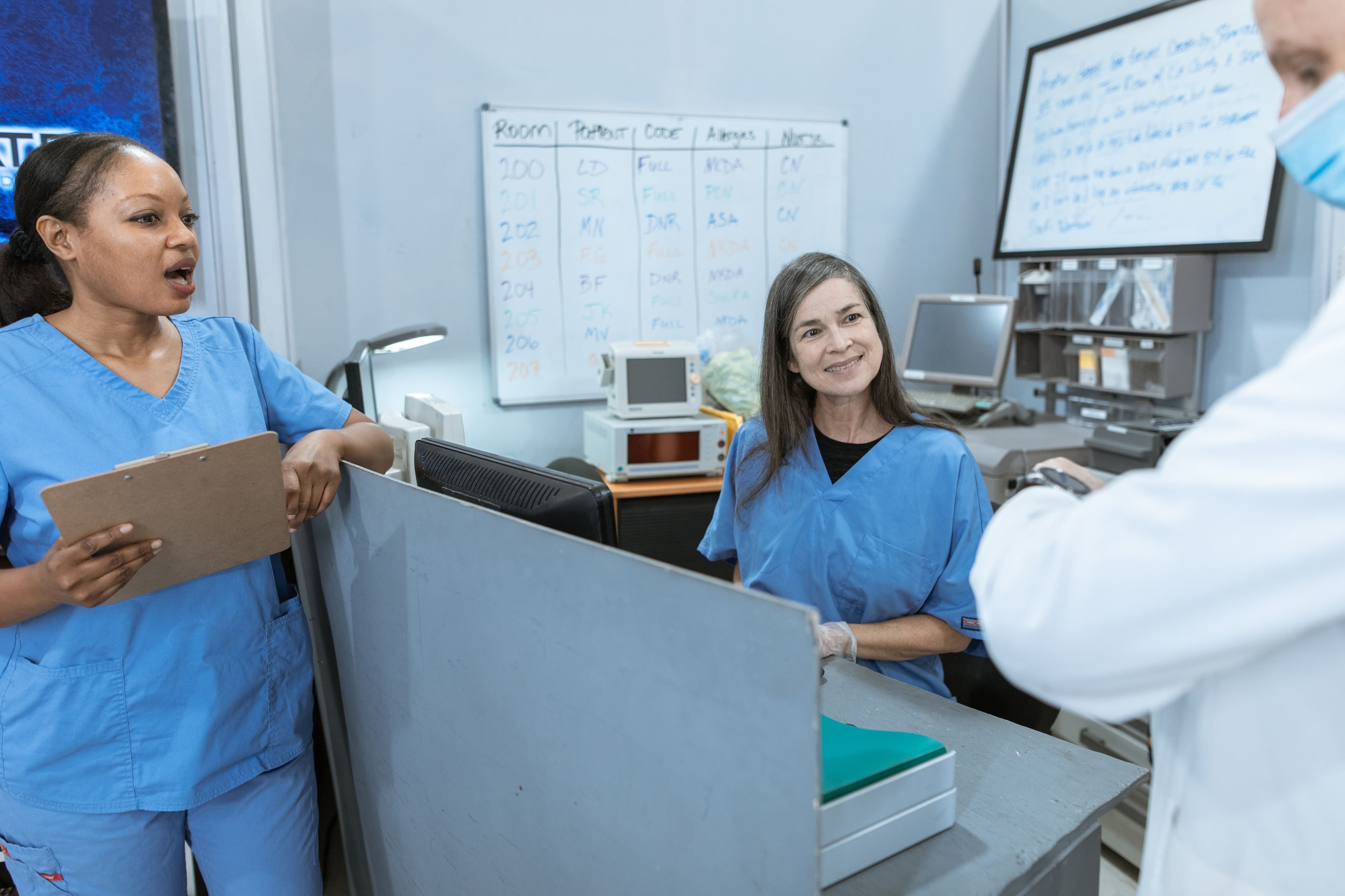 Clinical care team coordinating patient information at a nurses' station